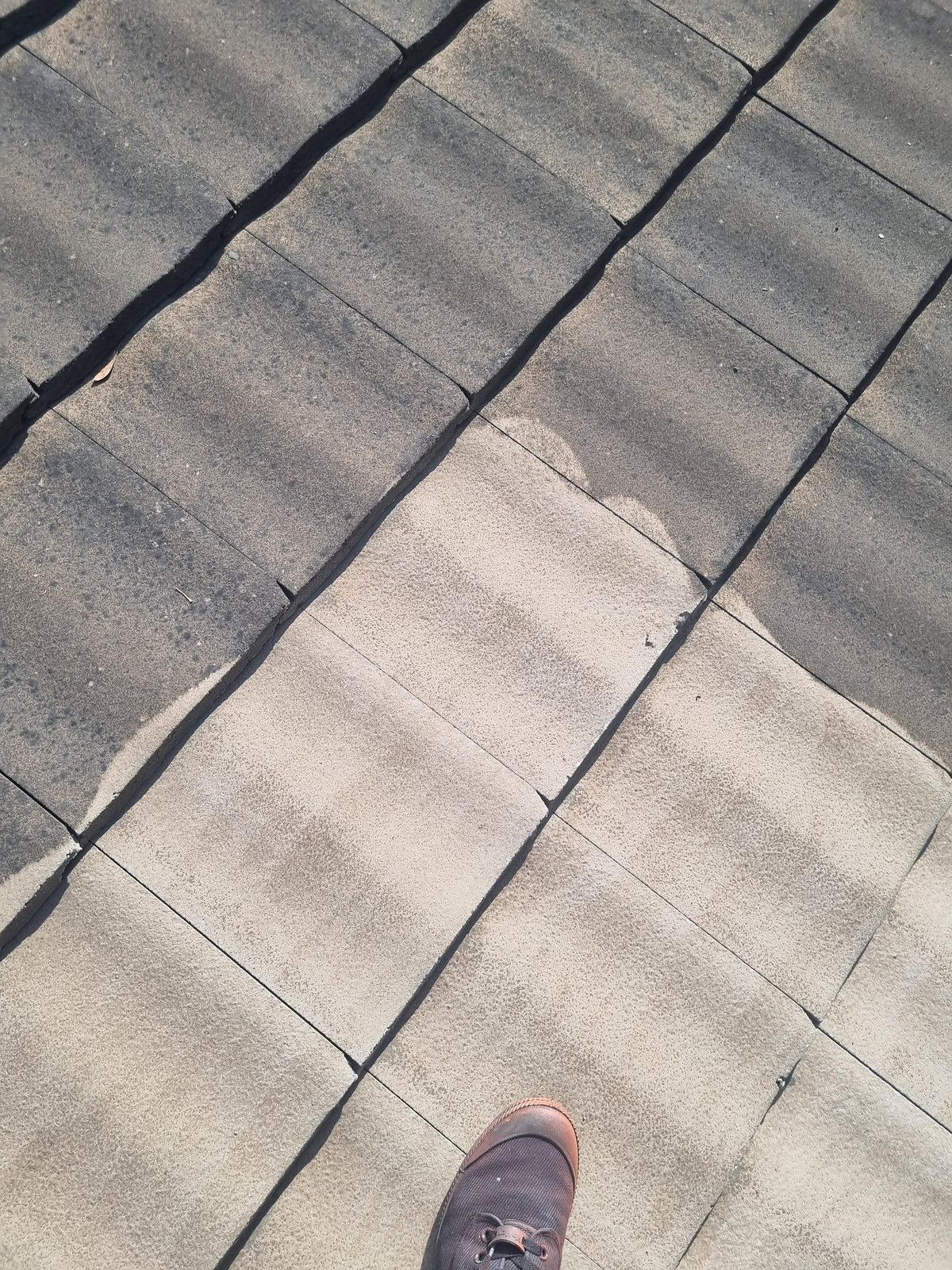 Close-up of concrete roof tiles, dirty section versus freshly cleaned section