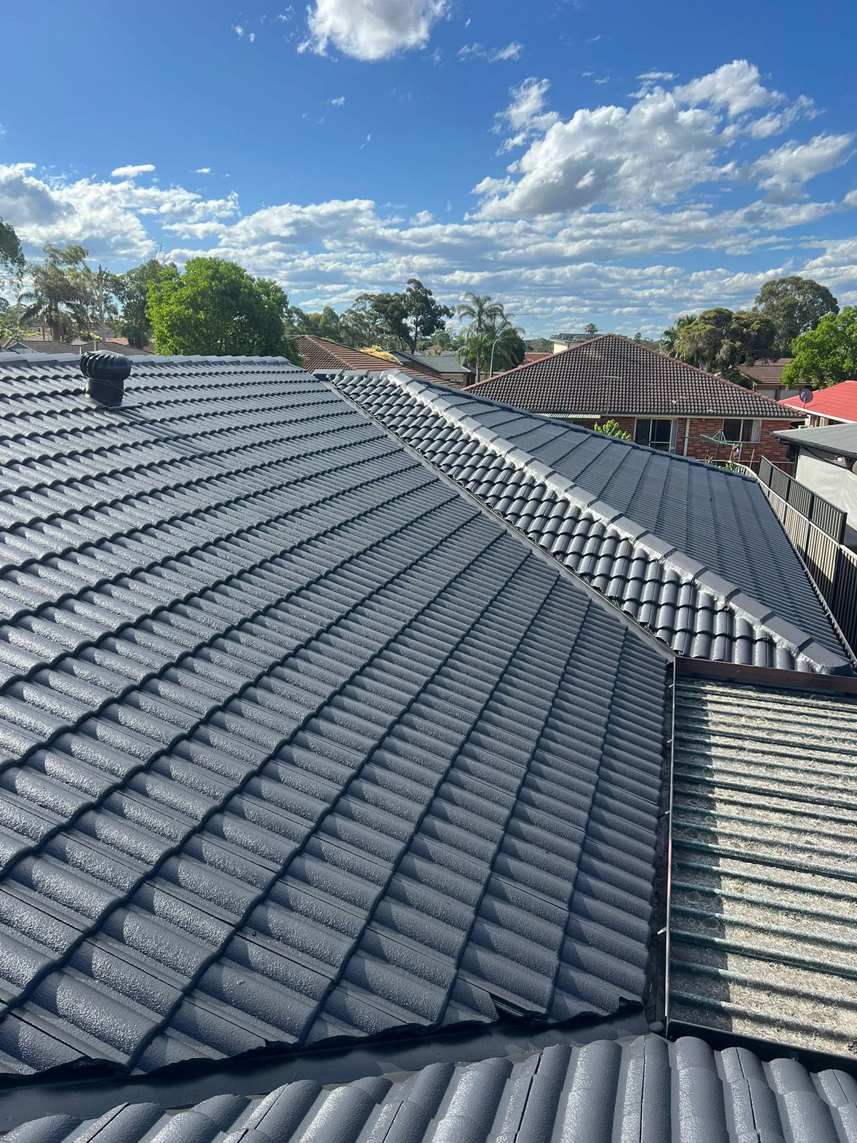 Completed charcoal roof painting project across adjoining rooflines